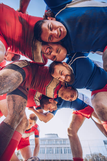 Rugby players standing on a plying field in a row.