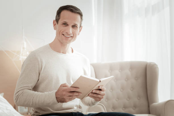 istock Satisfied smart man holding a book and smiling. 942238260