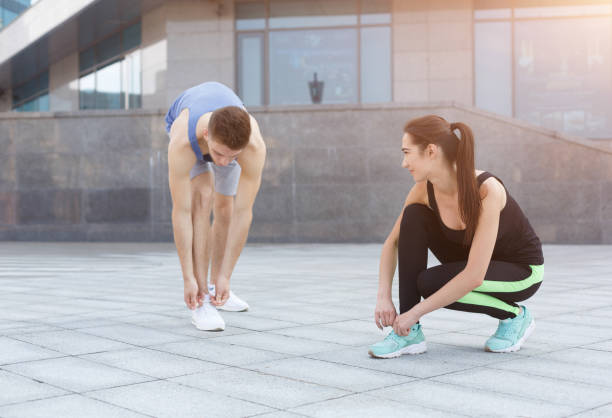 istock Concentrated man and woman tying shoelaces before running 942240986