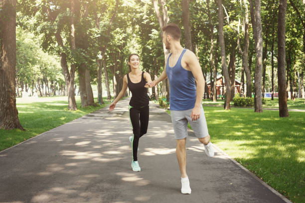 istock Young couple jogging in green park, copy space 942241540