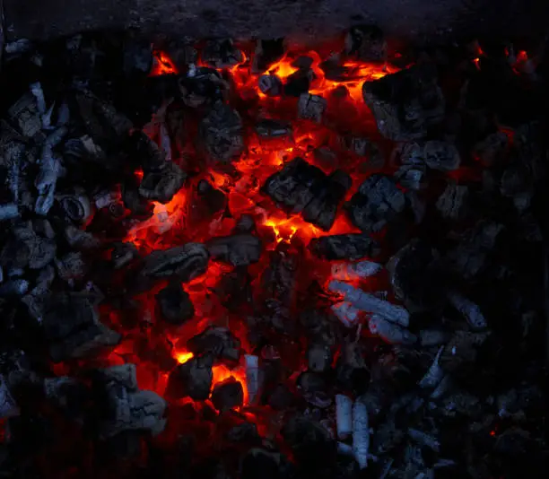 Close-up of red burning embers in the dark, view from above