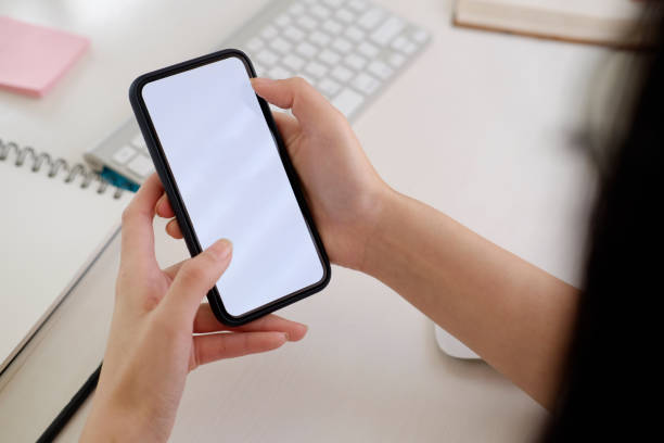 istock Blank screen mobile phone in female hands on desk 942247440