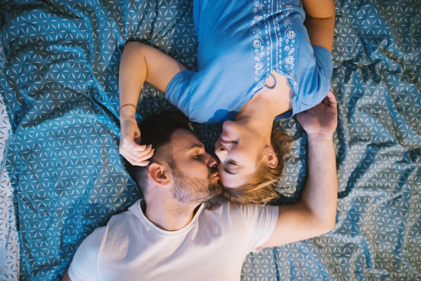 istock Cheerful happy romantic couple lying on the bed with bodies in opposite ways while cuddling and kissing. Relationship and weekend goals. 942247696