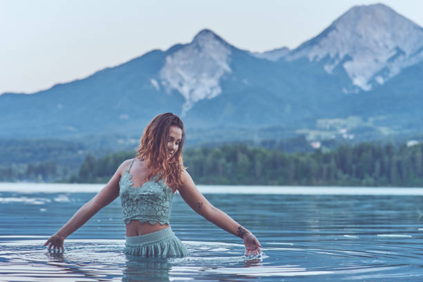 Lady at the lake Red head lady sitting at a beautiful italian lake in a white robe. back shoulder tattoos for women pictures stock pictures, royalty-free photos & images