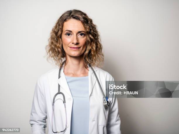 Portrait Of Female Doctor Against Wall In Hospital Stock Photo - Download Image Now - Doctor, Portrait, Female Doctor