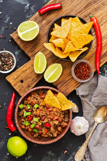 istock Chili con carne with nachos with meat and chips on rustic background. Mexican dish, top view 942271088