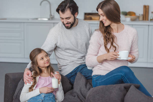 istock parents and daughter with milk and coffee on sofa 942273170