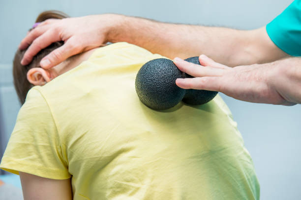 femme à la physiothérapie recevant ball massage du thérapeute. un chiropraticien traite la colonne vertébrale thoracique du patient dans le cabinet médical. chiropratique ostéopathie, neurologie. mise au point sélective, close up. - massage ball photos et images de collection