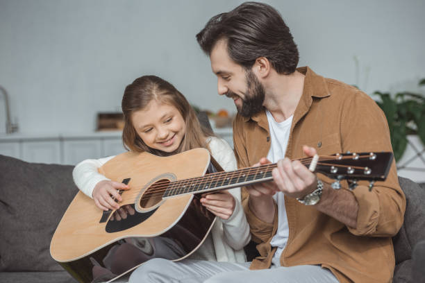 istock happy father teaching daughter playing acoustic guitar 942282562