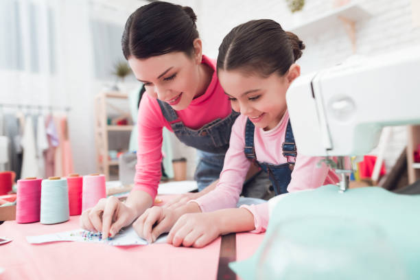 A little girl and woman together construct clothes. stock photo