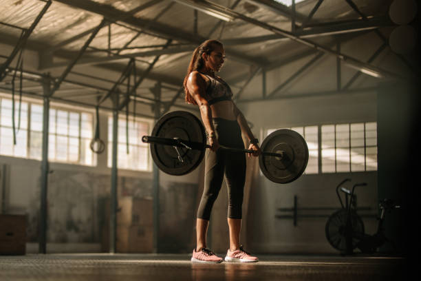 gym woman lifting heavy weights in gym Strong female athlete holding a barbell in her hands. gym woman lifting heavy weights in gym. woman weight training stock pictures, royalty-free photos & images