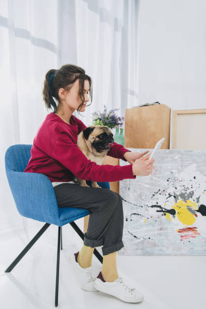 istock Attractive young girl using tablet and holding dog at home 942287298