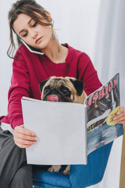 istock Attractive young girl talking on the phone and hugging pug dog 942290318