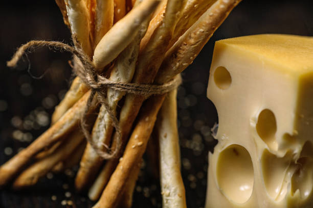 Cheese and Grissini breadsticks on wood background.