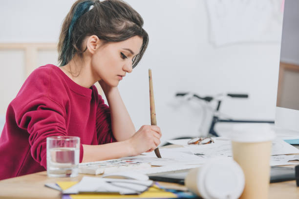 istock Attractive young girl drawing sketches by working table 942300770