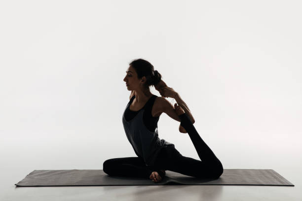 istock side view of woman practicing yoga and doing king pigeon on white 942306654