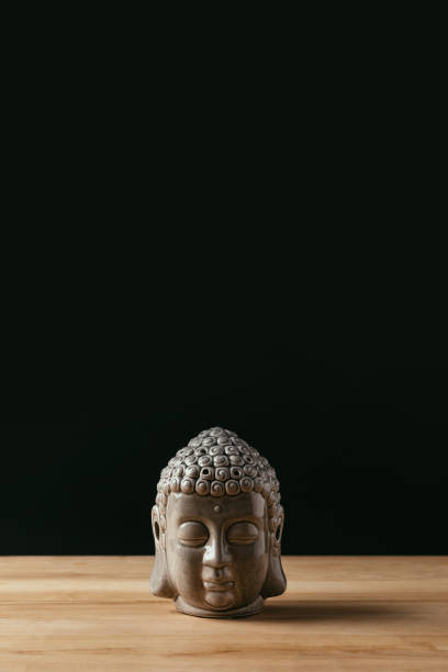 istock Sculpture of buddha head on wooden table 942308846