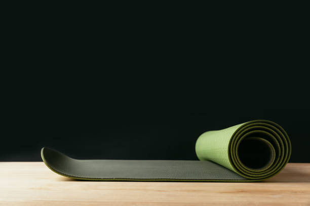 istock green rolled yoga mat on wooden table on black 942309410