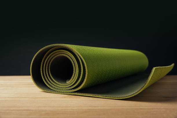 istock green rolled yoga mat on wooden surface on black 942309464