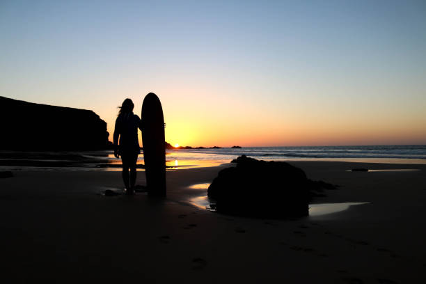 istock Surfer girl in sunset light on the beach 942309616