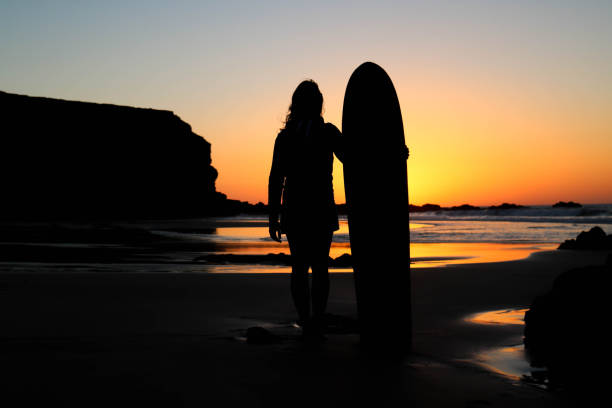 istock Surfer girl in sunset light on the beach 942309632