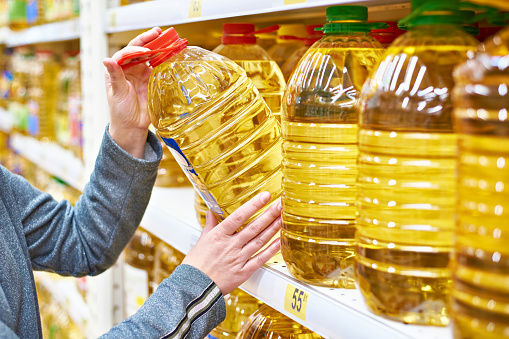 Botella grande de aceite en comprador de la mano en el supermercado photo