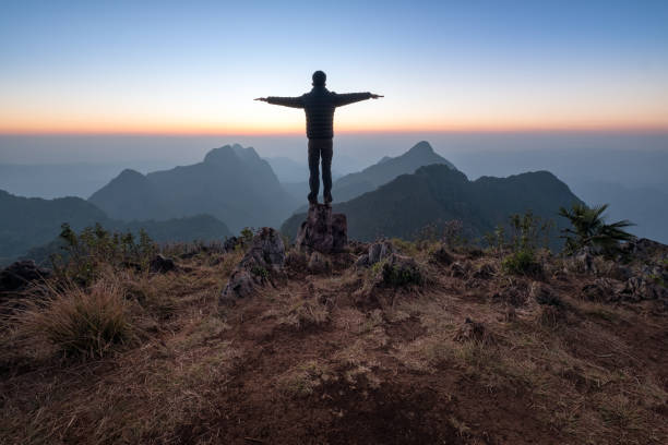 istock Man With Arms Outstretched Standing Against Sky During Sunset 942314036