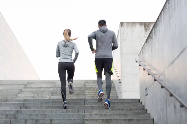 Photo of couple running upstairs on city stairs
