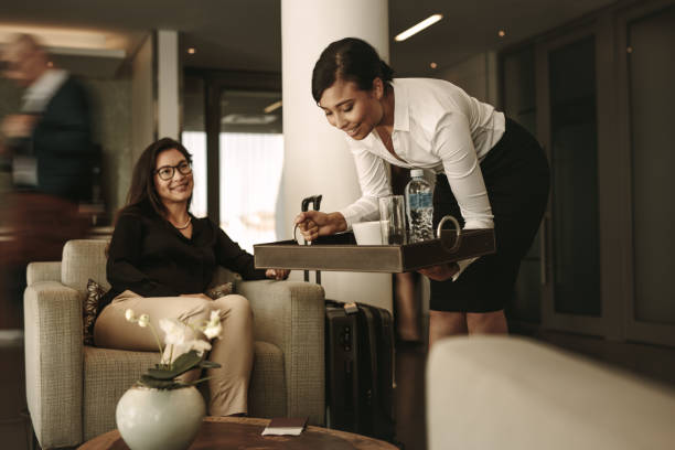 Airport lounge waitress serving coffee to female passenger Business lounge waitress serving coffee to female passenger at waiting area. Business woman relaxing and waiting for flight at airport departure lounge. airport departure area stock pictures, royalty-free photos & images