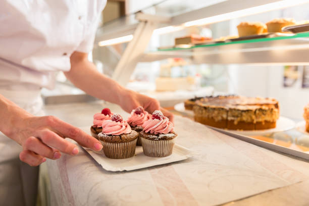 istock Women putting muffins on display in bakery shop 942331012