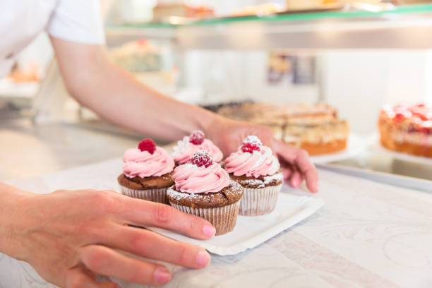 istock Women putting muffins on display in bakery shop 942331260