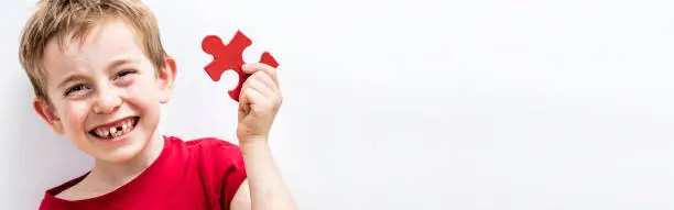 Photo of giggling toothless child enjoying finding a jigsaw for fun difference