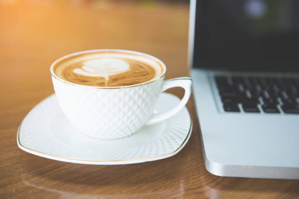 istock Cup of coffee and laptop on wooden table. 942337720
