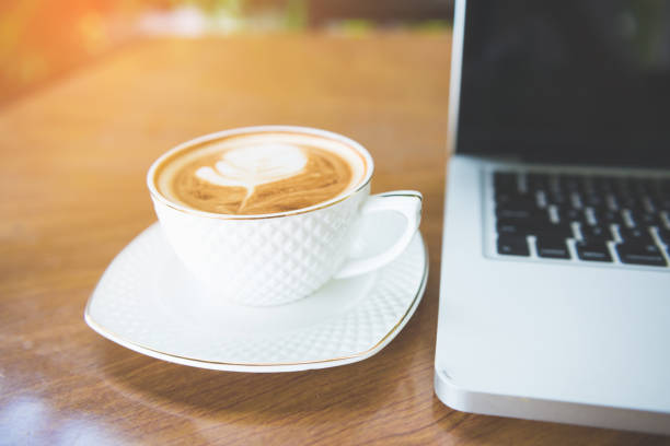 istock Cup of coffee and laptop on wooden table. 942338270