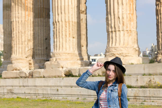 jovem viajante feminino está olhando para a câmera. no fundo é o famoso templo de zeus em atenas. - monument athens greece people travel - fotografias e filmes do acervo