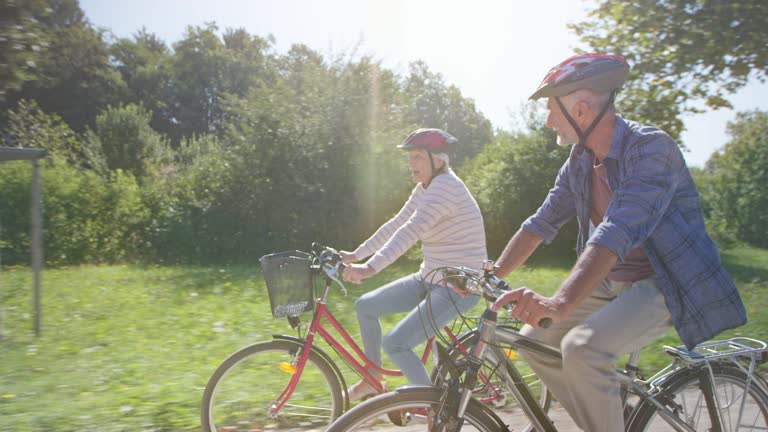 TS Senior couple cycling through the sunny park