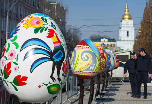 Kyiv / Ukraine - April 4, 2018: The Ukrainian pysanky festival. Two policemen take photo of the giant easter eggs.