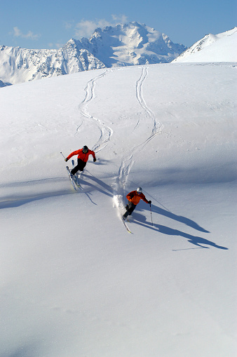 Pair of skis in snow with copy space. Red skis standing in snow with winter mountains in background. Winter holiday vacation and skiing concept.