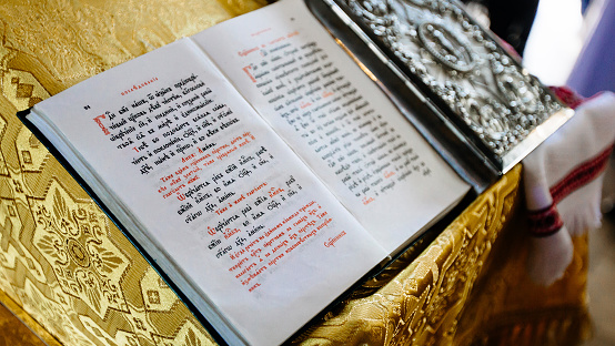 Dnipro, Ukraine - August 06, 2017: bible on reading-desk or lectern, sacred lectern in the church decorated with golden friezes and ornaments,old open book - the gospel in Old Russian language
