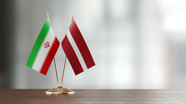 istock Iranian And Latvian Flag Pair On A Desk Over Defocused Background 942381172