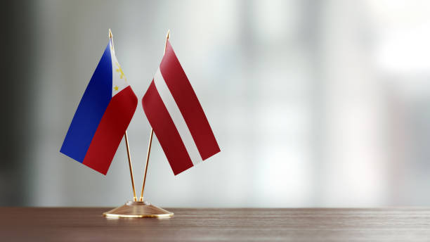 istock Philippines And Latvian Flag Pair On A Desk Over Defocused Background 942381510