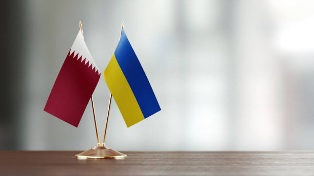 istock Qatari And Ukrainian Flag Pair On A Desk Over Defocused Background 942384140
