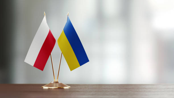 Polish and Ukrainian flag pair on desk over defocused background. Horizontal composition with copy space and selective focus.
