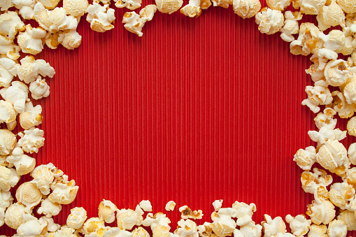 Salty popcorn on red paper background, unhealthy food, movie food
