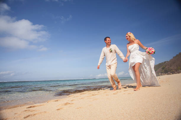 istock Wedding couple just married holds hands and walking at beach 942390684
