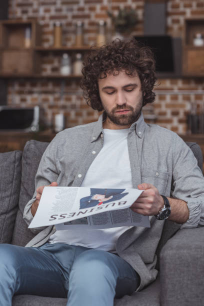 istock handsome man reading business newspaper at home 942393846
