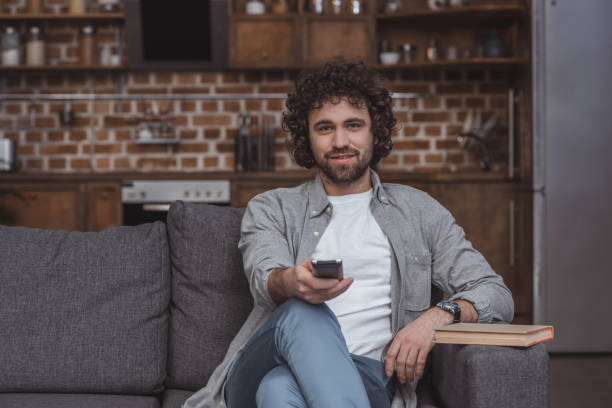 istock handsome man changing tv channels with remote control at home 942396784