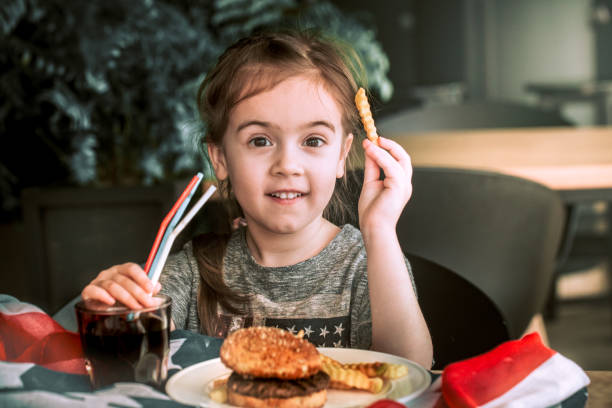 istock little girl in cafe with burger 942400768