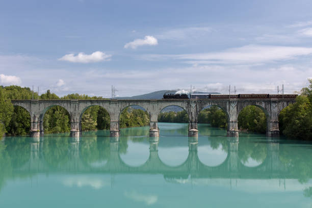 istock Old Steam Train crossing Soca River over Gorizia Stone Bridge, Italy 942403080