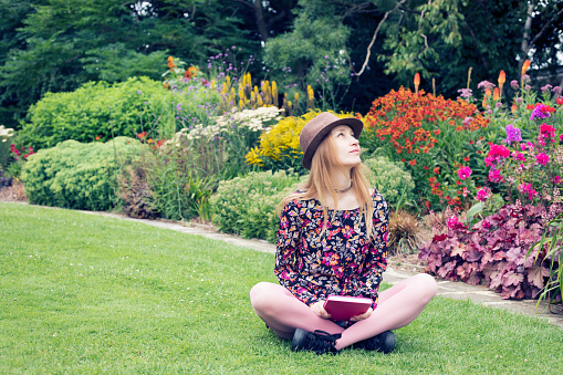 Young girl reading book in beautiful garden